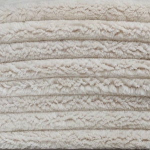May include: A close-up of a stack of white fluffy towels. The towels are soft and plush, and they are perfect for drying off after a bath or shower.