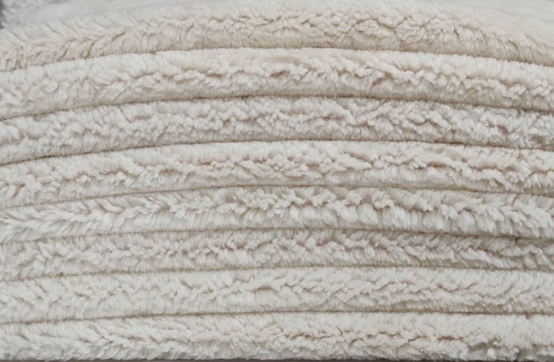 May include: A close-up of a stack of white fluffy towels. The towels are soft and plush, and they are perfect for drying off after a bath or shower.