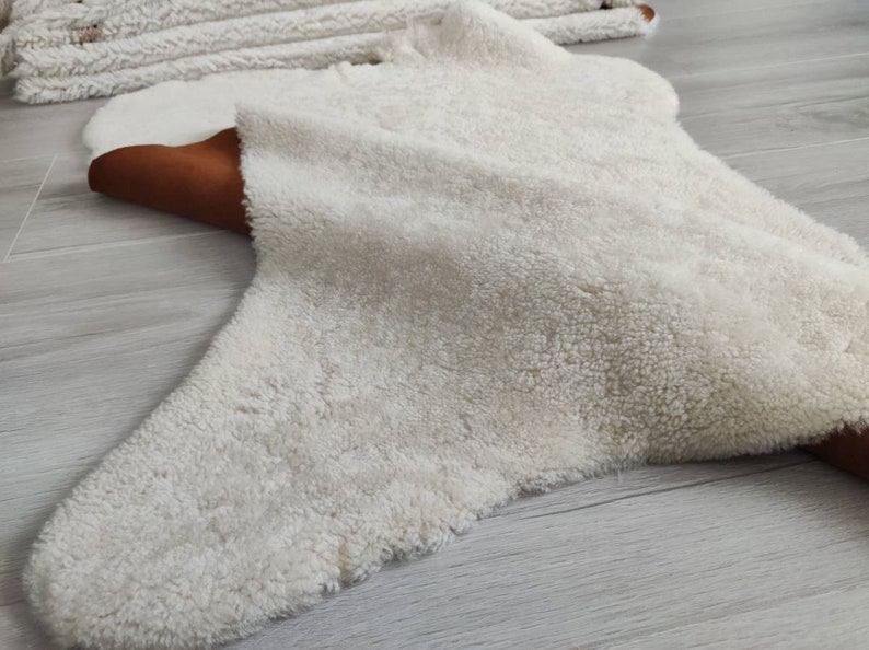 May include: A white fluffy rug with a brown leather border. The rug is shaped like a star and has a soft, plush texture.