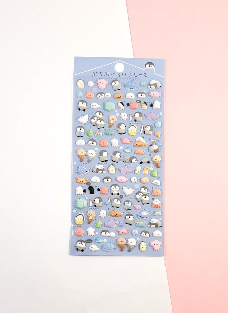 Puede incluir: Una hoja de pegatinas hinchadas de colores con ping&uuml;inos, ballenas, peces y otras criaturas marinas. Las pegatinas est&aacute;n sobre un fondo azul y tienen el texto japon&eacute;s "ぷちぷにぷちシール" que se traduce como "Puchi Puchi Seal".