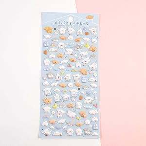 Puede incluir: Una hoja de pegatinas hinchadas con adorables ovejas de dibujos animados con varias expresiones y accesorios. Las pegatinas est&aacute;n sobre un fondo azul claro con el texto "ぷちぷちにぎゅっとシール" en japon&eacute;s.