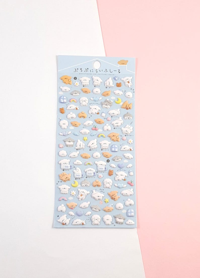 Puede incluir: Una hoja de pegatinas hinchadas con adorables ovejas de dibujos animados con varias expresiones y accesorios. Las pegatinas est&aacute;n sobre un fondo azul claro con el texto "ぷちぷちにぎゅっとシール" en japon&eacute;s.