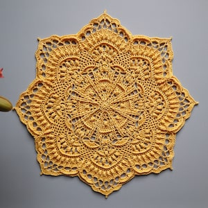Puede incluir: Un encaje de ganchillo amarillo con un diseño de estrella. El encaje está hecho con un patrón delicado e intrincado y tiene un borde festoneado.