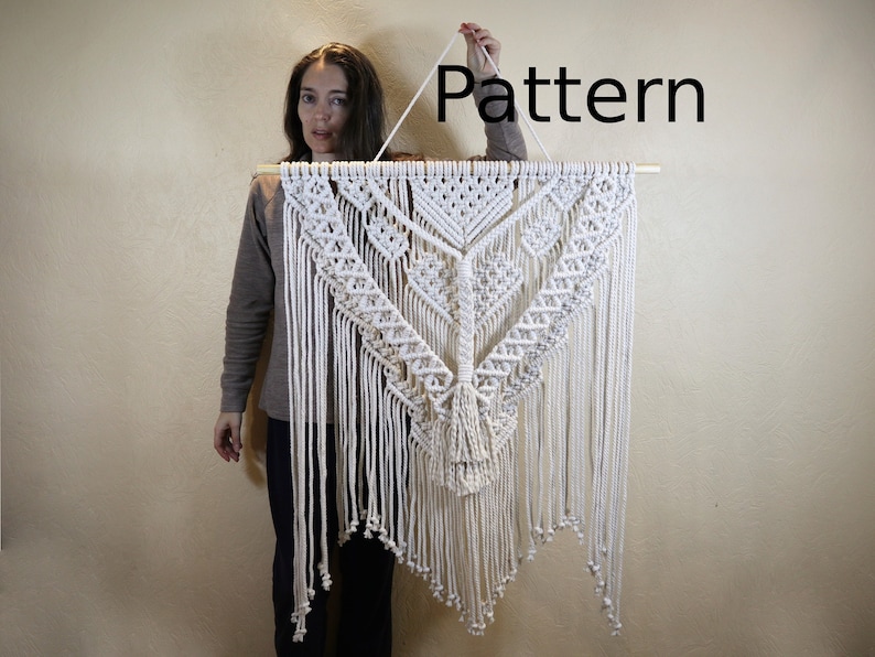 May include: A white macrame wall hanging with a geometric pattern and fringe. The hanging is approximately 4 feet tall and 3 feet wide. The word "Pattern" is written in black text above the hanging.