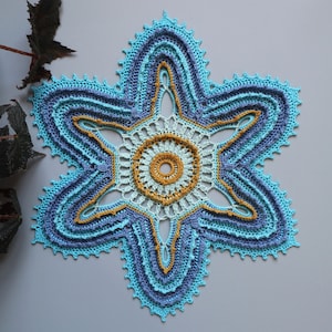May include: A crocheted doily in the shape of a star with blue, teal, and yellow accents.