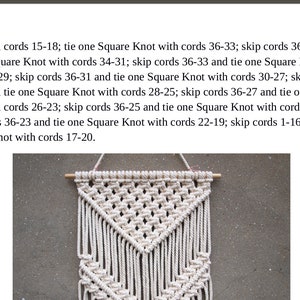 Op de afbeelding: Een witte macram&eacute; wandhanger met een driehoekige vorm. De wandhanger is gemaakt met een reeks vierkante knopen en is bevestigd aan een houten stok.