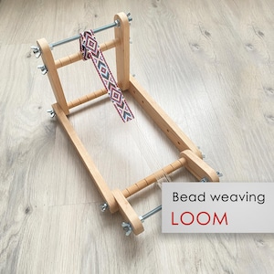 Può includere: Un telaio in legno per la tessitura di perline con un motivo di perline rosso, bianco e blu. Il telaio è realizzato in legno naturale e ha un design semplice. Telaio per la tessitura di perline.