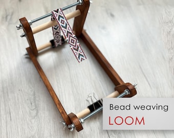 May include: A wooden bead weaving loom with a beaded strap hanging from it. The loom has two wooden dowels and a metal frame. The text "Bead weaving LOOM" is visible in the image.
