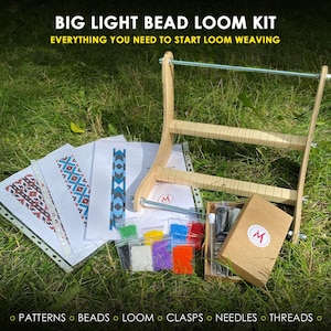 May include: A big light bead loom kit featuring a wooden loom frame with metal rods, several printed pattern sheets, small plastic bags containing assorted colorful beads, and a brown cardboard box with a circular logo containing the letter M.