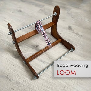 May include: A wooden bead weaving loom with a beaded strap in progress. The loom is made of brown wood and has two metal rods. The text "Bead weaving LOOM" is visible in the image.