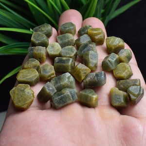 May include: A collection of green and yellow rough gemstones. The gemstones are faceted and have a variety of shapes and sizes.