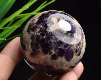 Peut inclure: Une grande sphère d'améthyste ronde et violette avec un centre blanc. La sphère est composée de nombreux petits cristaux facetés.