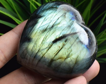 May include: A heart-shaped labradorite crystal with a blue-green iridescent sheen. The crystal is polished and smooth, with a natural, organic shape.
