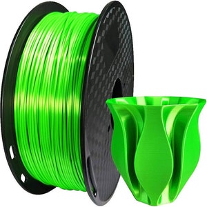 Pu&ograve; includere: Un rotolo di filamento verde brillante per la stampa 3D, con un oggetto stampato dello stesso colore. L'oggetto &egrave; un vaso con un design unico e organico.