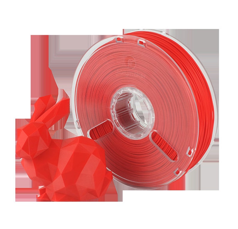 Pu&ograve; includere: Un rotolo di filamento rosso per la stampa 3D. Il filamento &egrave; avvolto attorno a un rotolo di plastica trasparente con un foro centrale. Una statuetta di coniglio rossa stampata in 3D &egrave; in primo piano.