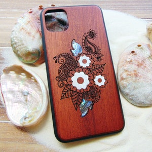 May include: A wooden phone case with a dark red finish and a laser-etched design of a floral pattern with white accents. The design includes a paisley pattern and a flower with a mother-of-pearl center.