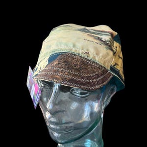 May include: A white ceramic mug with a black handle and the text "But First, Coffee" in a black, handwritten-style font. The mug is on a white surface.