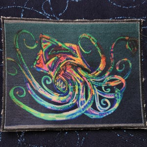 May include: A colorful, abstract, embroidered patch featuring a stylized octopus with swirling tentacles. The octopus is rendered in shades of green, blue, pink, and orange.