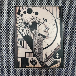 May include: A rectangular fabric patch featuring a black and cream abstract graphic design. The illustration includes geometric shapes, a large circle, honeycomb patterns, and small mushroom-like silhouettes, all bordered by a dark stitched edge.