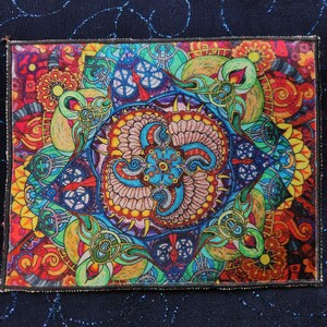 May include: A colorful square patch with a detailed mandala design featuring intricate patterns and swirls in shades of red, orange, yellow, green, blue, and purple.