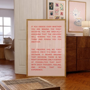 May include: A pink and white framed poster with a motivational quote in red text. The quote reads: "If you obsess over whether you are making the right decision, you are basically assuming that the universe will reward you for one thing and punish you for another. The universe has no fixed agenda. Once you make any decision, it works around that decision. There is no right or wrong. Only a series of possibilities that shift with each thought, feeling, and action, that you experience."