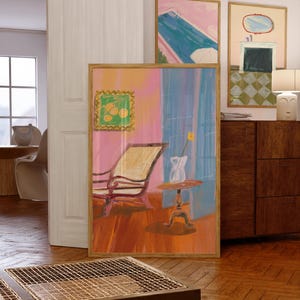 May include: An abstract painting in a wooden frame depicts a room with a chair, table, and a vase with a yellow flower. The color palette includes pink, blue, and orange. Additional framed art pieces are visible in the background, along with a wooden cabinet.