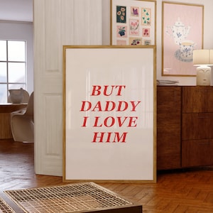 Pode incluir: Um pôster branco emoldurado com o texto "BUT DADDY I LOVE HIM" em letras vermelhas.