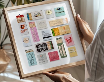 May include: A framed collection of matchbox labels featuring various Baltimore landmarks and businesses. The labels are colourful and feature a variety of designs, including illustrations, text, and logos. Some of the labels include the names "Baltimore Museum of Art", "Woodberry Kitchen", "Cafe Los Sueños", and "Peter's Inn".