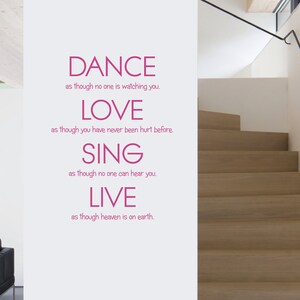 May include: A wall decal featuring pink text that reads: DANCE as though no one is watching you, LOVE as though you have never been hurt before, SING as though no one can hear you, LIVE as though heaven is on earth, applied to a white wall.