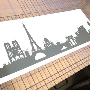 Puede incluir: Una silueta gris del horizonte de Par&iacute;s, con monumentos emblem&aacute;ticos como la Torre Eiffel, la Catedral de Notre Dame y el Arco del Triunfo.
