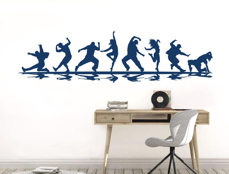 May include: A dark blue wall decal featuring a horizontal row of eight silhouettes of people in various dynamic dance poses. Each figure is depicted in motion, with a mirrored reflection effect appearing directly beneath the line of dancers.