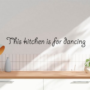 May include: A white kitchen wall with a black vinyl decal that reads "This kitchen is for dancing".