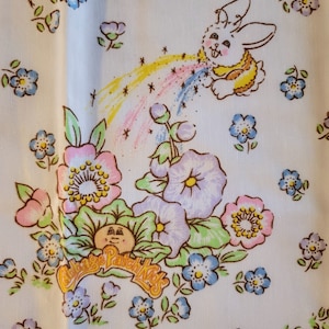 May include: White fabric with a repeating pattern of flowers and a bunny rabbit. The bunny is blowing a rainbow and the text "Cabbage Patch Kids" is printed on the fabric.