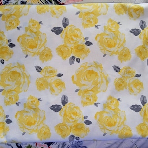 Puede incluir: Tela blanca con un patrón floral amarillo. La tela presenta un patrón repetitivo de rosas amarillas con hojas grises.