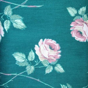 May include: A teal fabric with a floral pattern featuring pink roses and green leaves.