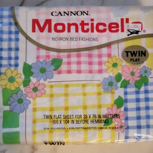 May include: A package of Cannon Monticello twin flat bed sheets in a patchwork design with yellow, pink, blue, and green gingham patterns and floral accents. The package includes a twin flat sheet for a 39 x 76 inch mattress (66 x 104 inches before hemming). The sheet is made of 50% polyester and 50% cotton.