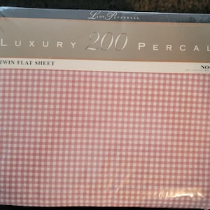 May include: A pink and white gingham twin flat sheet with the text "Luxury 200 Percale" and "No-Iron" printed on the packaging. The sheet is made of 60% cotton and 40% polyester.