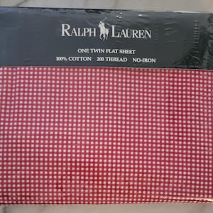 May include: A packaged Ralph Lauren twin flat sheet. The sheet is red and white gingham, made of 100% cotton with a 200 thread count. The packaging is black with the Ralph Lauren logo and product information.
