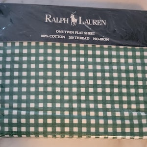 May include: A green and white gingham flat sheet packaged in plastic. The packaging has the Ralph Lauren logo and the text "One Twin Flat Sheet, 100% Cotton, 200 Thread, No-Iron."