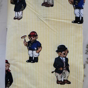 May include: A yellow and white vertically striped fabric featuring a repeating pattern of teddy bears dressed in various outfits, including polo gear with helmets and mallets, navy blazers, and red berets, printed across the entire surface.