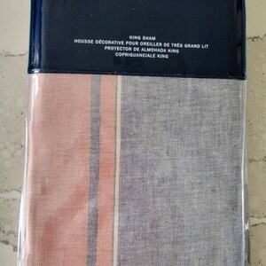 May include: A pink and gray striped king-size pillow sham with the Ralph Lauren logo and text in French and Spanish. The text reads "King Sham, Housse Décorative pour Oreiller de Très Grand Lit, Protector de Almohada King, Copriguanciale King."