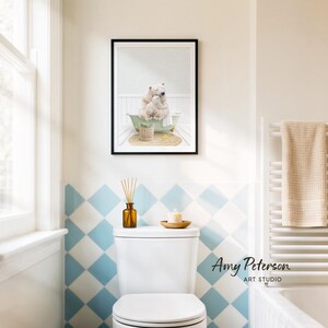 a bathroom with a white toilet, a framed picture of a polar bear and its cub, and a towel rack.