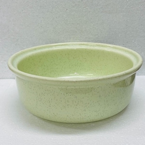 Peut inclure: Un bol en céramique vert clair avec un motif moucheté. Le bol a une forme arrondie, un large bord et une finition lisse et brillante. L'intérieur est d'une nuance de vert plus claire.