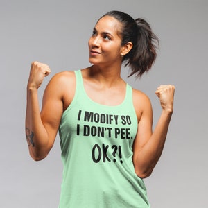 May include: A light green tank top with the text "I MODIFY SO I DON'T PEE. OK?!" in black. The tank top is a sleeveless style.