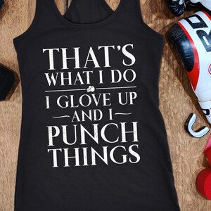 May include: Black tank top with white text that reads "THAT'S WHAT I DO I GLOVE UP AND I PUNCH THINGS." Includes boxing gloves, hand wraps, and two 6 kg dumbbells.