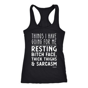 May include: Black racerback tank top with white text that reads "THINGS I HAVE GOING FOR ME RESTING BITCH FACE, THICK THIGHS & SARCASM." The word "#obsessed" is printed below the text.