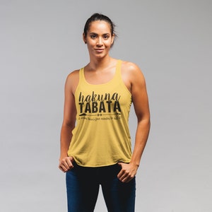 May include: Mustard yellow tank top with the text "hakuna TABATA" in black script. Below the text is the phrase "it means there's four minutes to kill!" in a smaller font. The tank top has a racerback design.