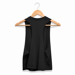 May include: A black vest top suspended from a wooden clothes hanger. The top features a scoop neckline and wide armholes. The background is plain white.
