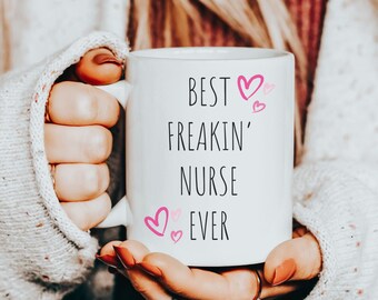 May include: White ceramic mug with black text that reads "Best Freakin' Nurse Ever" with pink hearts.