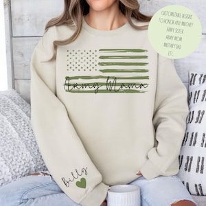 May include: A beige sweatshirt with a green and white American flag design and the text "Army Mama". The left sleeve has the word "Billy" and a green heart.